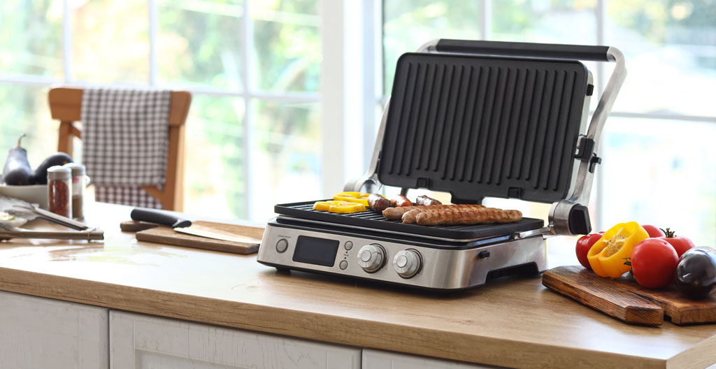 Une personne de dos prépare des légumes dans une cuisine ouverte lumineuse avec une grande fenêtre